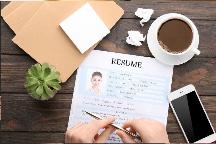 A resume on a desk with a cup of coffee.